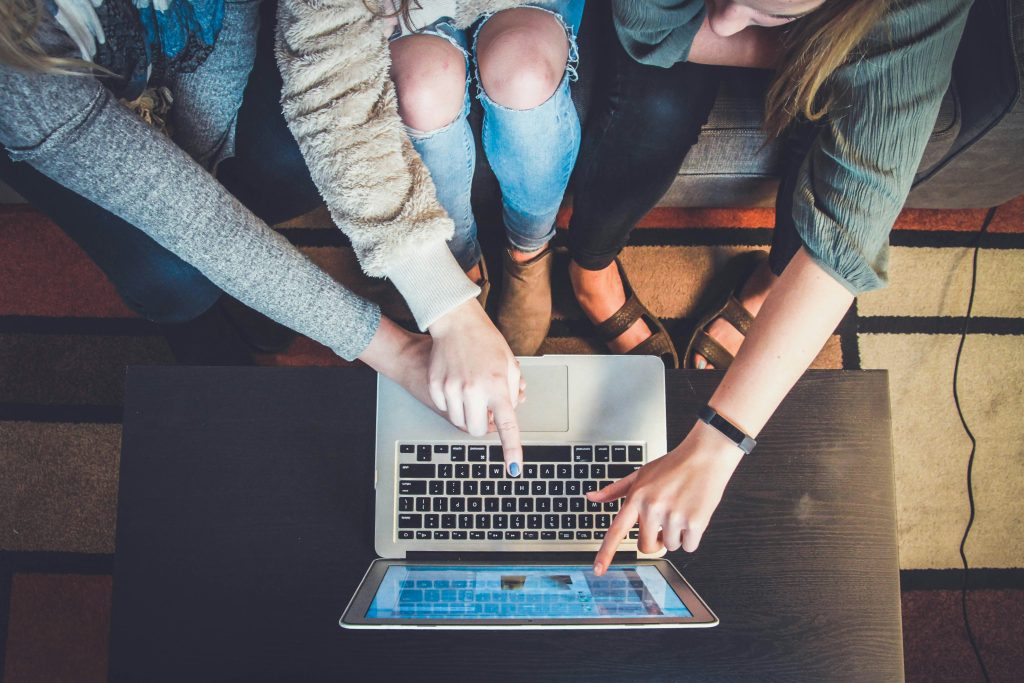 THREE PEOPLE POINTING TO A COMPUTER